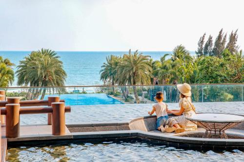 汕尾汕尾保利希尔顿逸林酒店的两人坐在游泳池旁的沙发上