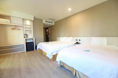 斗六市致丽伯爵酒店的配有白色床单的酒店客房内的两张床