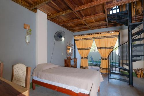埃斯孔迪多港Nopalero Suites Hostel的一间卧室设有一张床和一个螺旋楼梯