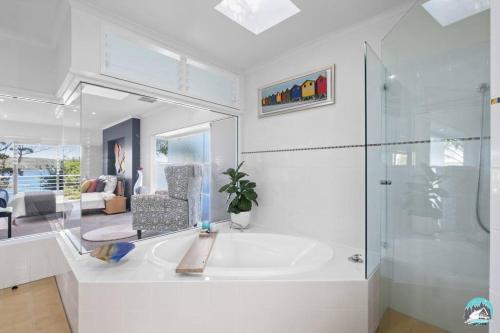 Daleys PointAircabin - Daleys Point - Waterfront Retreat House的白色的浴室设有浴缸和玻璃淋浴间。