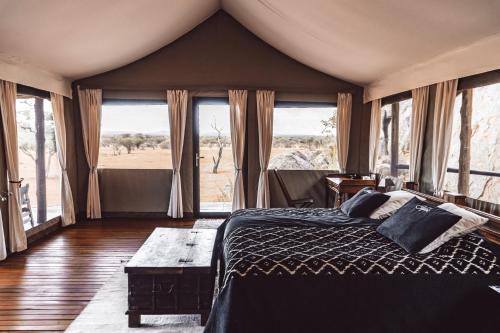 奥乔Ohorongo Tented Camp的一间设有床铺的卧室,位于带窗户的房间内