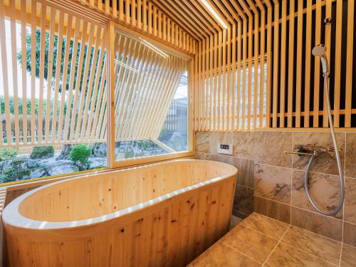 Fukusaki姫路城の奥座敷　築400年の宿 鐵十郎（登録文化財）的带窗户的浴室内的木制浴缸