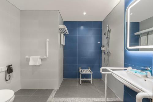 长春长春生态广场智选假日酒店的浴室铺有蓝色瓷砖,设有卫生间和水槽。