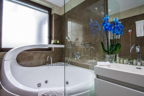 索非亚Best Western Plus Olives City Hotel - Free Parking的带浴缸、水槽和蓝色鲜花的浴室