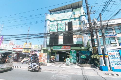 马尼拉RedDoorz at Ranchotel Bayanan Alabang的骑摩托车的人在建筑物前的街道上骑摩托车