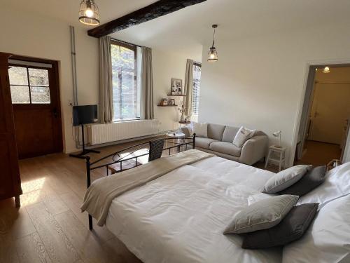 马斯特里赫特B&B Sjaanderhof的卧室配有一张白色的大床和一张沙发。