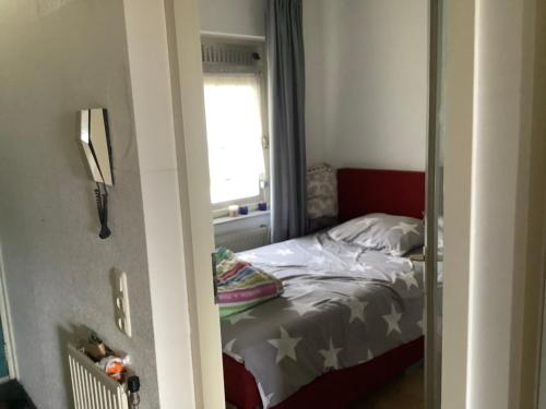 海牙Geniet van de rust en uitzicht的一个小房间的小床,设有窗户
