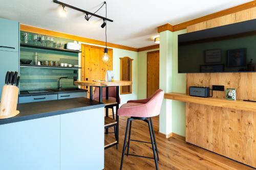 罗伊特Wellness Aparthotel "Lechlife" incl Infinity Pool - 400m zum Lift的一间带柜台的厨房和一间带粉色椅子的酒吧