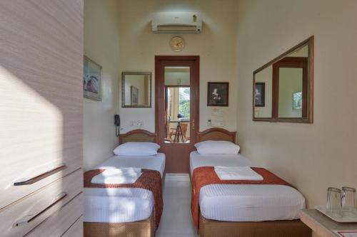 孟买Elphinstone Hotel的带两张床和镜子的客房