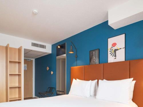贝桑于潘港宜必思巴耶贝森港酒店的一间卧室配有一张蓝色墙壁的床