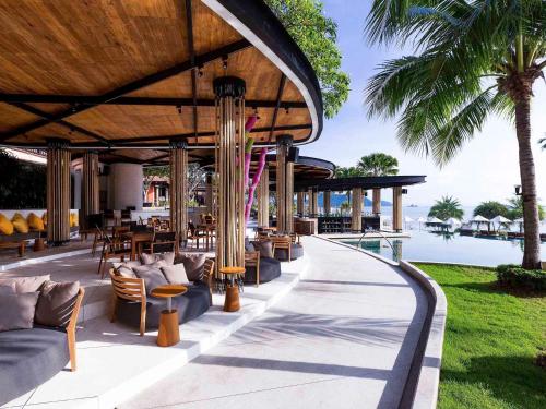 攀瓦海滩Pullman Phuket Panwa Beach Resort的一个带桌椅的度假庭院和一个游泳池