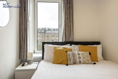 霍伊克Riverside的一间卧室配有一张带黄色枕头的床和一扇窗户