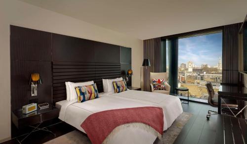 伦敦art'otel London Hoxton, Powered by Radisson Hotels的一间卧室设有一张大床和一个大窗户