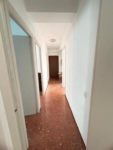 阿尔么丽亚piso en zapillo的一条空的走廊,有白色的墙壁和红色的地板