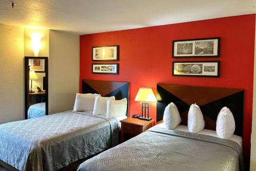 尚佩恩Howard Johnson by Wyndham Urbana的红色墙壁的酒店客房内的两张床