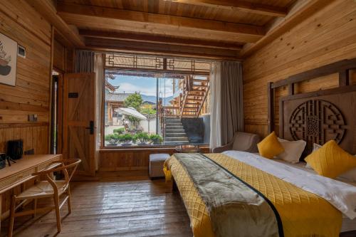 丽江丽江拾田民宿的一间卧室配有一张床、一张书桌和一个窗户。