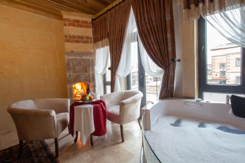 乌奇希萨尔Milagro of Cappadocia的带浴缸、两把椅子和一张桌子的浴室