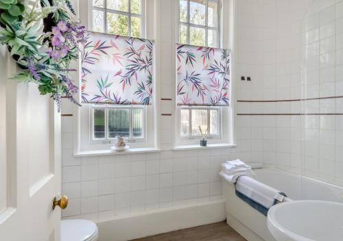 StradsettThe Lake House - Crimplesham Hall的带浴缸和水槽的浴室以及2扇窗户。