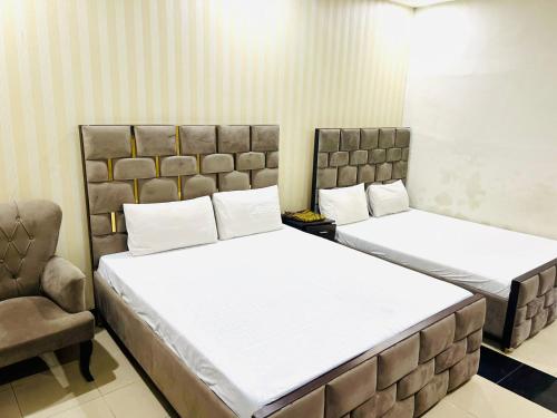 伊斯兰堡Oriole Luxury Hotel的一间卧室配有两张床和椅子