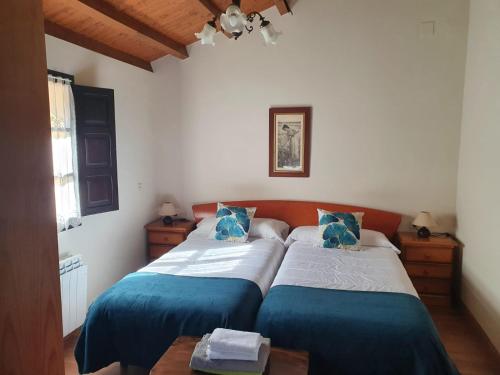 San Juan de la ArenaComplejo turístico Las Mimosas del Nalon, LOS NOVALES的一间卧室配有两张带蓝白色床单的床