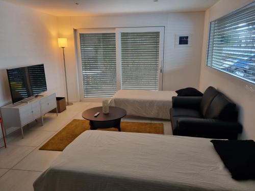 穆尔滕Elegant Suites Murten的酒店客房设有两张床、一张沙发和一张桌子。