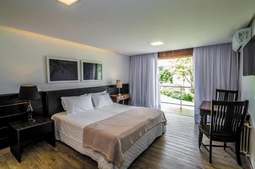 卡内拉卡内拉大酒店的一间卧室配有一张床、一张书桌和一个窗户。