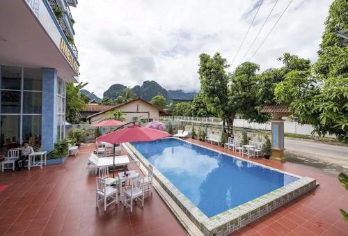 万荣ViengSaVanh Hotel的酒店游泳池设有椅子和遮阳伞