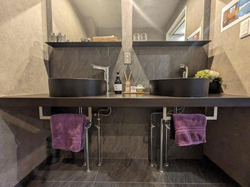 京都ホテル SHUNJU Dosse 1日1組様限定的浴室在带紫色毛巾的台面上设有2个水槽