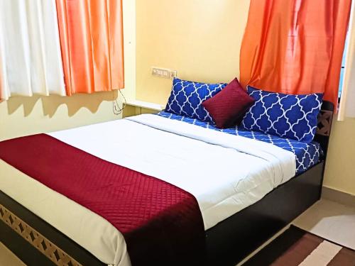 班加罗尔Golden Magnolia Homestay的一张带红色和蓝色枕头的床