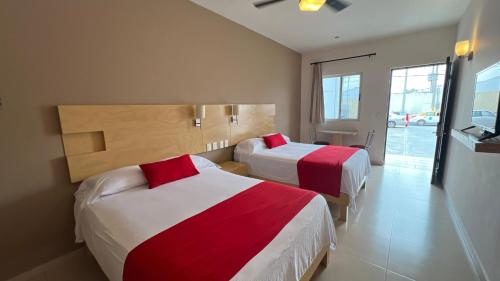 Cadereyta JiménezNova Hotel的酒店客房带两张红色和白色的床单