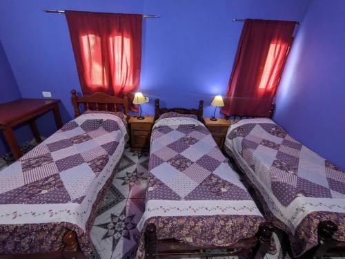 伊鲁亚Hostal Mary的配有红色窗帘的客房内的两张床