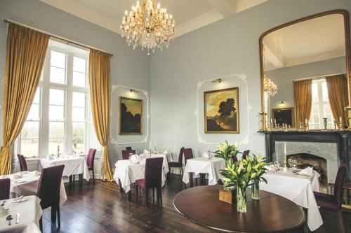 Kinnitty基尼缇城堡酒店的一间配备有白色桌椅和吊灯的餐厅