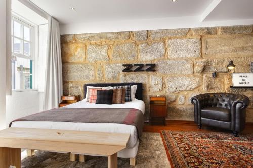 波尔图波尔图雅致舒适一室公寓酒店的一间卧室设有一张床和石墙