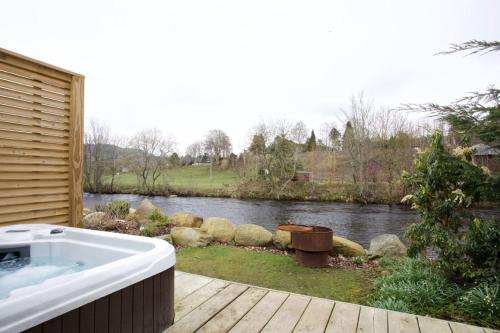 克里夫Braidhaugh Holiday Lodge and Glamping Park的浴缸位于河边的甲板上
