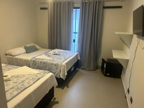 乌巴图巴Pousada do Francês的酒店客房设有两张床和窗户。