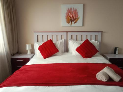 东伦敦Edladleni Guesthouse Quigney的一张带红色枕头和红色毯子的床