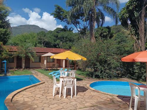 莫埃达Pousada Maravilhas da Serra的游泳池旁的天井配有椅子和遮阳伞。