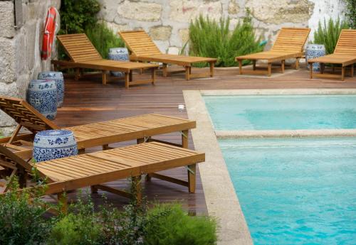 波尔图Saboaria Boutique Hotel Porto的游泳池旁的一排木凳