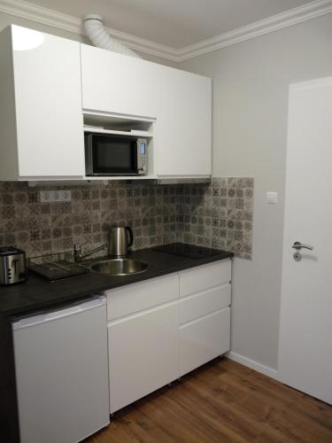 埃格尔ILLA Apartments的白色的厨房配有水槽和微波炉
