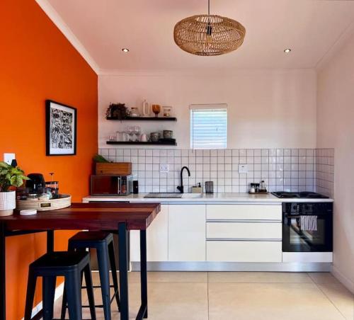 温特和克Garden Oasis的厨房设有橙色墙壁和木桌
