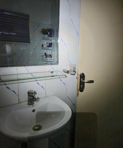 拉各斯Quiet and comfortable home的浴室设有白色水槽和镜子