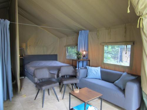 HensbroekLuxe safaritent op Landgoed de Leijen的客厅配有沙发和帐篷内的桌子