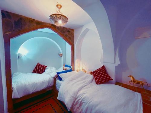 舍夫沙万Riad Bab Mahruk的带拱形窗户的客房内的两张床