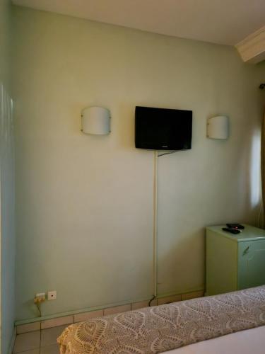 利伯维尔Association LES PYRAMIDES GABON的一间设有壁挂式电视的房间,配有一张床