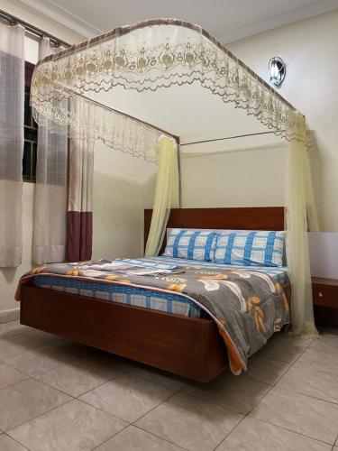 坎帕拉MiniPalais Bukoto的一张带天蓬的床