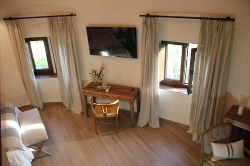 Horcajuelo de la SierraHOTEL RURAL SANTUI的客房设有书桌、床、桌子和窗户。