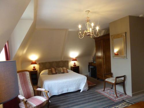 滨海圣布里阿克Le Clos du Pont Martin的一间卧室配有一张床、两把椅子和一个吊灯