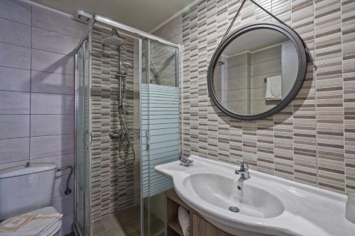 罗希姆诺Lefkoniko Beach & Icarus Suite Apts的一间带水槽、镜子和卫生间的浴室