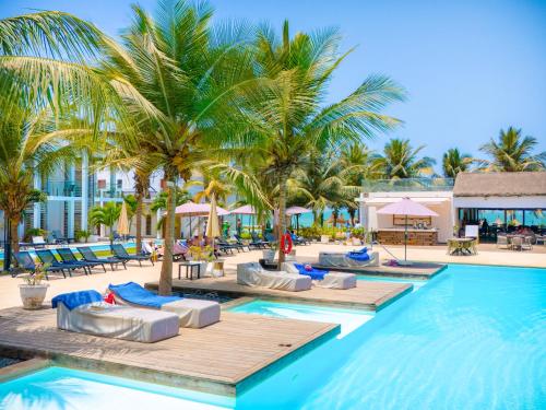 科图Tamala Beach Resort的一个带躺椅和棕榈树的游泳池
