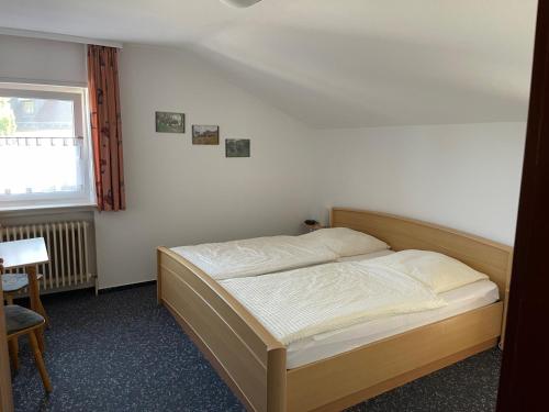 辛斯海姆Hotel Gästehaus Sonne的一间卧室配有一张床、一张桌子和一个窗户。